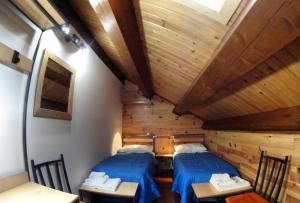 two beds in a small room with wooden ceilings at Case Gemmellaro - Family&Friends in Nicolosi