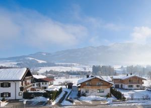 un village dans la neige avec des montagnes en arrière-plan dans l'établissement Bergblick, à Fischen im Allgäu