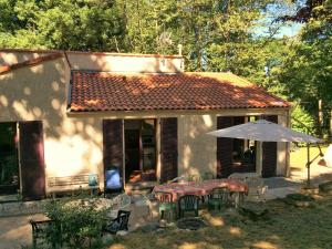 a house with a table and an umbrella in the yard at Studio duplex 2 Lac des Montagnès in Mazamet