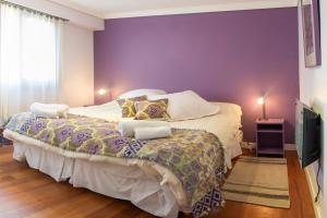 1 dormitorio con 1 cama grande y pared morada en Casa Labian Cabañas en San Carlos de Bariloche