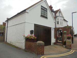 een wit huis met een bruine deur en bloemen bij Holywell Apartments in Eastbourne