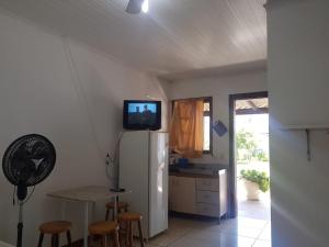 a kitchen with a refrigerator and a tv on the wall at Pousada Praia do Barco in Capão da Canoa