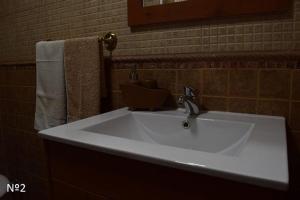 Un lavabo blanco en un baño con espejo. en Los Ayales, en Huelamos 30 fotos más