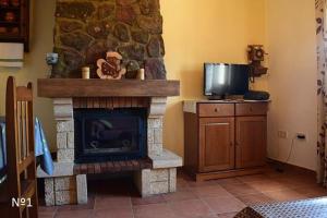 sala de estar con chimenea de piedra y TV en Los Ayales, en Huelamos