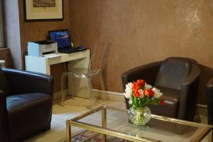 uma sala de estar com duas cadeiras e uma mesa com um vaso de flores em Hotel Pierre Nicole em Paris