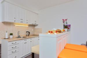 eine Küche mit weißen Schränken und einem orangefarbenen Stuhl in der Unterkunft Apartment Castellino in Kotor