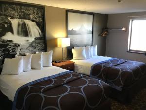 una habitación de hotel con 2 camas y un cuadro en la pared en Super 8 by Wyndham Miles City, en Miles City