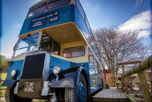 um autocarro azul de dois andares estacionado num quintal em Ceridwen Glamping, double decker bus and Yurts em Llandysul