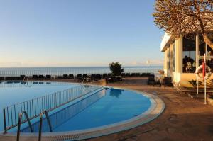 a large swimming pool next to a building and the ocean at Duas Torres - Appartment in Funchal
