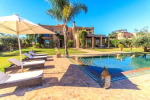 a pool with chairs and an umbrella next to a house at Villa 69 Samanah Golf Country Club in Ala el Ma