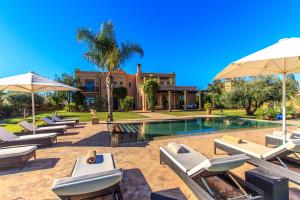 a pool with lounge chairs and umbrellas in front of a house at Villa 69 Samanah Golf Country Club in Ala el Ma
