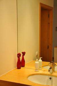 ファフェにあるCasas da Costeiraのバスルーム(シンク、赤い花瓶2本付)