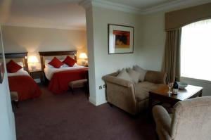 a hotel room with two beds and a couch at Old Ground Hotel in Ennis