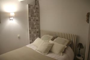 um quarto branco com uma cama com almofadas brancas em La perle des Bains em Trouville-sur-Mer