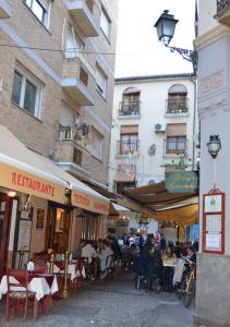 a group of people sitting at tables in front of buildings at Granada CENTRO al pie de la Alhambra y el Albaicín in Granada