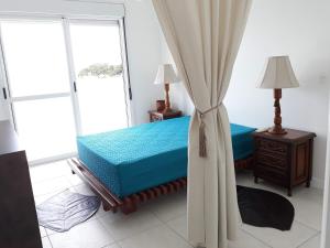 a bedroom with a bed and a large window at casa frente do mar in Governador Celso Ramos