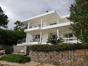 a large white house with a stone wall at casa frente do mar in Governador Celso Ramos