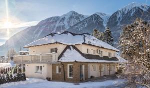 a house covered in snow with mountains in the background at Villa Ambach in Oetz