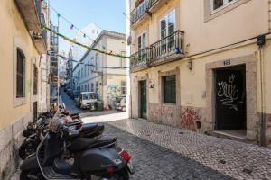 uma fila de scooters estacionadas numa rua com graffiti em Living Bairro Alto II em Lisboa