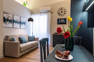 Una sala de estar con una mesa con flores y un sofá. en Four Elements Apartments, en Catania