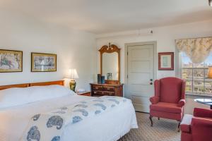 um quarto com uma cama, uma cadeira e uma janela em First Colony Inn em Nags Head