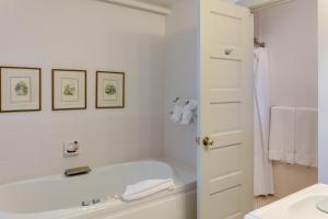 a white bathroom with a tub and a sink at First Colony Inn in Nags Head