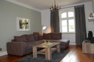 a living room with a brown couch and a table at Ferienwohnung ehemalige Revierförsterei "Morgensünn" in Kuhstorf