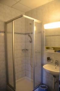 a shower with a glass door next to a sink at Hotel Restaurant Bahnhof in Schüpfen