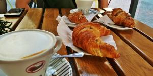 a wooden table with croissants and a cup of coffee at Affittacamere Gallurà in Calangianus
