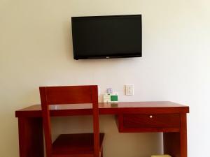 einen Schreibtisch mit Stuhl und einen TV an der Wand in der Unterkunft Hotel Santiago in Jalpan de Serra