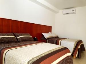 two beds in a hotel room with twothirdsessions at Hotel Santiago in Jalpan de Serra