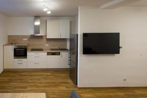 a kitchen with white cabinets and a flat screen tv at eder-home in Reisenberg