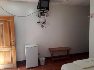 a room with a tv on the wall and a table at Hospedaje Mother Fanny in Puerto Villamil