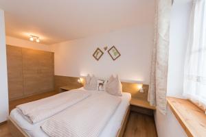 a bedroom with a white bed and a window at Bio-Bergbauernhof Hubgut in Zell am See