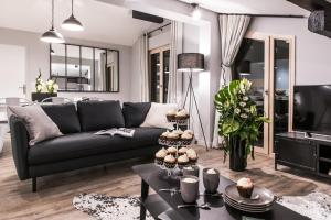 a living room with a black couch and a table at Résidences Alticimes in Brides-les-Bains