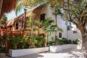 a house with palm trees in front of it at Kin Ha Tulum Hotel in Tulum