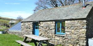 a stone cottage with a blue door and a picnic table at Woodend Schoolhouse in Broughton in Furness