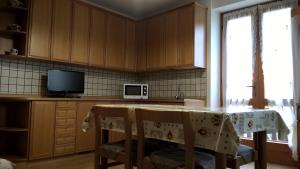 a kitchen with a table with chairs and a microwave at Appartamenti Fabila in Castello Tesino +8 photos