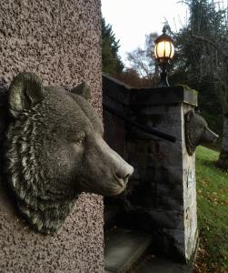 
a statue of a bear sitting on top of a fire hydrant at Highland Bear Lodge & Luxury Bear Huts in Drumnadrochit
