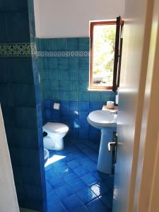 a blue tiled bathroom with a toilet and a sink at Casa Anna - Capo Perla Apartments in Capoliveri +56 photos
