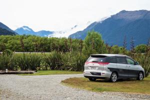 a car parked on the side of a road near a mountain at Haast River Motels & Holiday Park in Haast