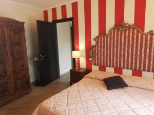 ein Schlafzimmer mit einem Bett und einer rot-weißen gestreiften Wand in der Unterkunft B&B Al Calcandola in Sarzana