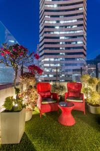 a red and white vase filled with flowers next to a tall building at Hotel Regina in Bogotá