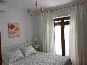 a white bedroom with a bed and a window at Casa Calle Alta Maria Bajo in Vejer de la Frontera