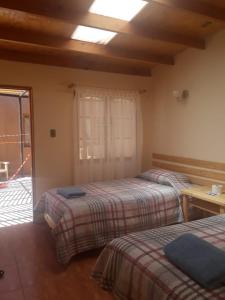 sypialnia z 2 łóżkami, stołem i oknem w obiekcie CASA MACAW w mieście San Pedro de Atacama