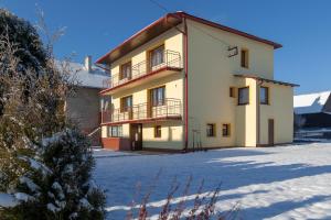 een groot wit gebouw met een balkon in de sneeuw bij AGROTURYSTYKA U JURKA in Tylicz