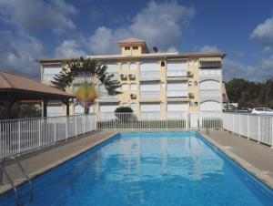 un hotel con piscina di fronte a un edificio di L'Hibiscus piscine et plage a Sainte-Luce