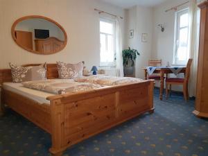 Schlafzimmer mit einem großen Holzbett und einem Spiegel in der Unterkunft Landhotel Nonnenroth in Hungen