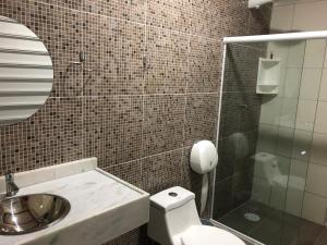 Un baño con inodoro, lavabo y espejo. en Maragogi Suítes, en Maragogi 52 fotos más
