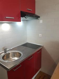 - une cuisine avec un évier et des placards rouges dans l'établissement Heliopolis F39, au Cap d'Agde